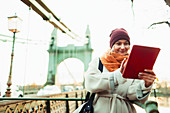 Woman using digital tablet on urban bridge