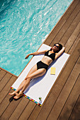 Woman sunbathing at summer poolside