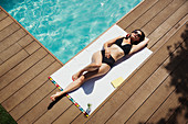 Woman relaxing, sunbathing at summer poolside