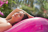 Serene woman relaxing on pink inflatable pool raft
