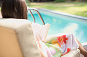 Woman relaxing, reading book at summer poolside