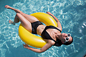 Woman floating on inflatable ring in summer swimming pool