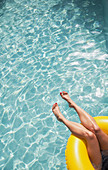 Woman with bare feet relaxing, floating in inflatable ring