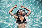 Serene woman floating in summer swimming pool