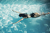 Woman in bikini swimming underwater in swimming pool