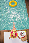 Woman in sun hat relaxing, sunbathing at summer poolside