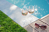 Rose wine and sunglasses at tranquil summer poolside
