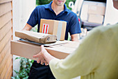 Deliveryman handing packages to woman at front door