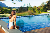 Serene woman in bathing suit relaxing at swimming pool