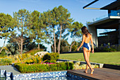 Woman in bathing suit walking on sunny, luxury patio