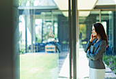 Businesswoman talking on smart phone at window