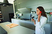 Woman talking on smart phone in kitchen
