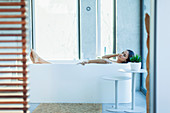 Serene woman relaxing in modern soaking tub