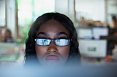 Focused businesswoman in eyeglasses working at computer