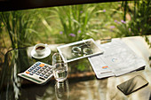 Calculator and tablet on table with coffee and paperwork