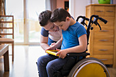 Boy with Down Syndrome using digital tablet in wheelchair