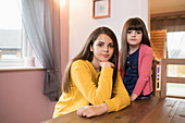 Portrait brunette sisters at dining table
