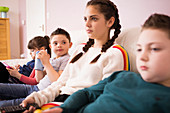 Brothers and sisters watching TV on living room sofa