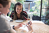 Women friends using smart phone at dining table