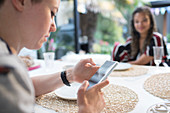 Woman using smart phone at dining table