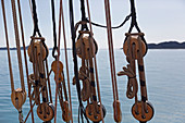 Wooden sailboat pulleys and rigging on ocean