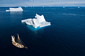 Ship sailing past icebergs on blue ocean Greenland