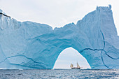 Ship sailing behind majestic iceberg formation on