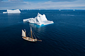 Ship sailing past majestic icebergs on blue