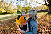 Portrait mother and son with autumn leaf in park