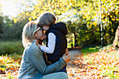 Affectionate mother and son hugging in autumn park