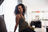 Portrait happy pregnant woman drinking green smoothie