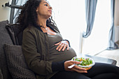 Tired pregnant woman eating salad