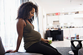 Pregnant woman drinking green smoothie in living room