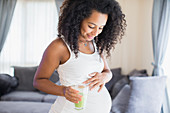 Happy pregnant woman drinking green smoothie