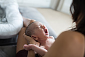 Mother holding crying newborn baby son