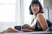 Portrait mother breastfeeding newborn baby son on sofa
