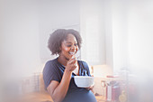 Happy pregnant woman eating in kitchen