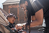 Happy father fastening toddler son in stroller