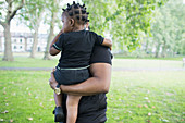 Father holding toddler son in park
