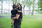 Portrait happy father holding toddler son in park