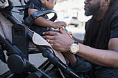 Father talking to toddler son in stroller