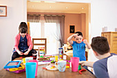 Brothers and sister playing with toys at dining table