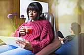 Woman drinking tea and using digital tablet