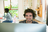 Young man with headset working at computer in home office
