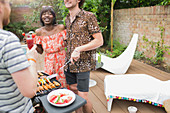 Happy multiethnic couple barbecuing on summer patio