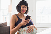 Happy pregnant woman using smart phone