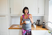 Portrait happy pregnant woman eating in kitchen