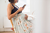 Pregnant woman in floral skirt holding stomach