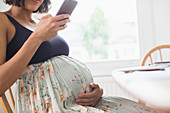 Pregnant woman in floral dress using smart phone