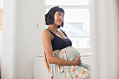 Thoughtful pregnant woman holding stomach